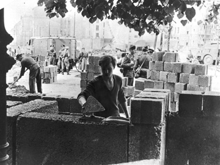 FILE - In this Aug. 13, 1961 file photo  a worker builds parts of the  a wall between the eastern and the western part of Berlin. AP Photographer Peter Hillebrecht was on assignment in Berlin as the construction of the Berlin Wall starts on Aug. 13, 1961 and he was one of the first photographers to  cover this historic event. When the wall was first built, nobody knew what was going to happen next. Many people were afraid that the wall would serve as a provocation and turn to the Cold War into a hot one. (AP Photo/File)